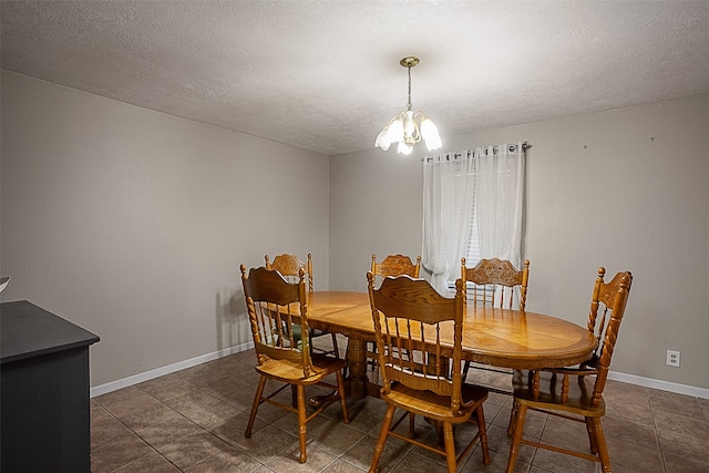 dining space with an inviting chandelier, dark tile patterned floors, and a textured ceiling