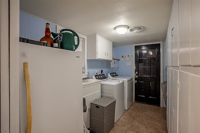 laundry room featuring cabinets, dark tile patterned flooring, and washing machine and dryer