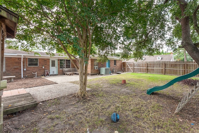 view of yard featuring a playground, cooling unit, and a patio area