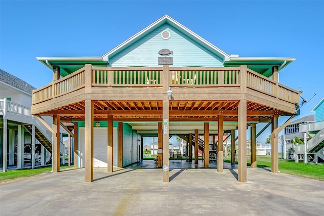 back of property with driveway, a garage, stairway, and a carport