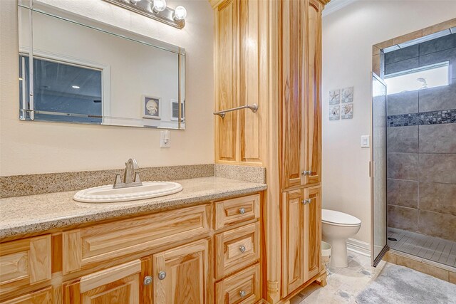 bathroom with a tile shower, vanity, and toilet