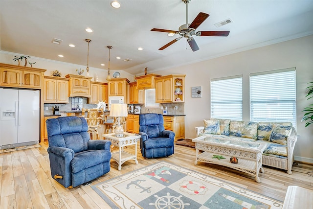 living area featuring visible vents, crown molding, light wood-type flooring, and a ceiling fan