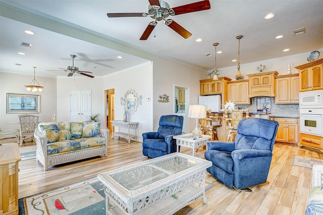 living room featuring light wood-type flooring, a ceiling fan, crown molding, and visible vents
