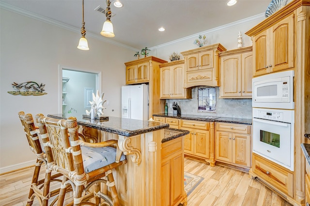 kitchen featuring crown molding, light wood finished floors, a breakfast bar, white appliances, and tasteful backsplash