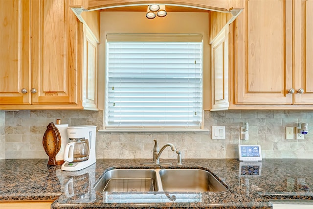 kitchen with dark stone countertops, light brown cabinets, tasteful backsplash, and sink