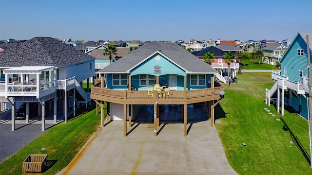 rear view of property featuring a residential view, concrete driveway, a carport, and a lawn