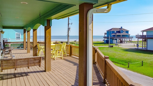 wooden terrace with a water view and a yard