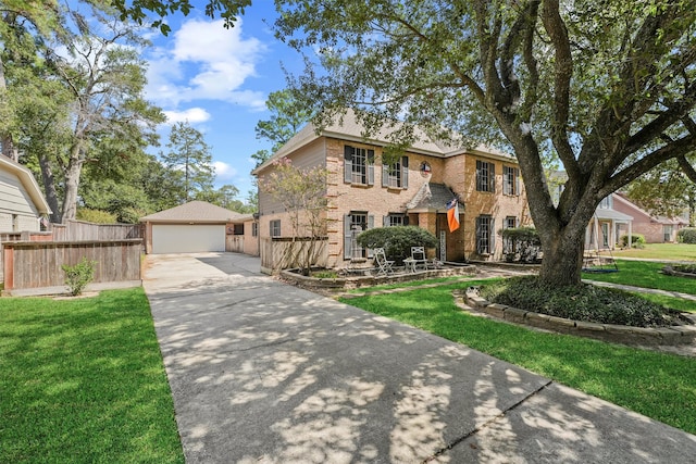 colonial house with a front lawn, brick siding, fence, and a detached garage