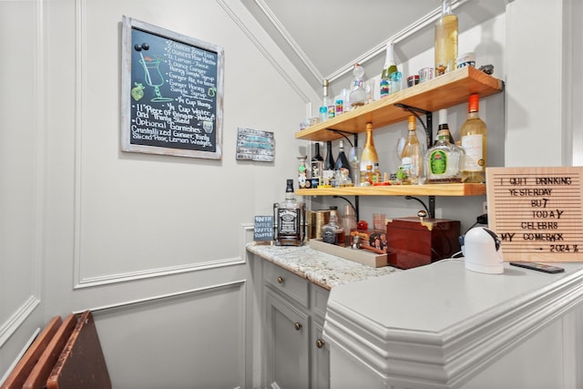 bar featuring light stone counters and crown molding