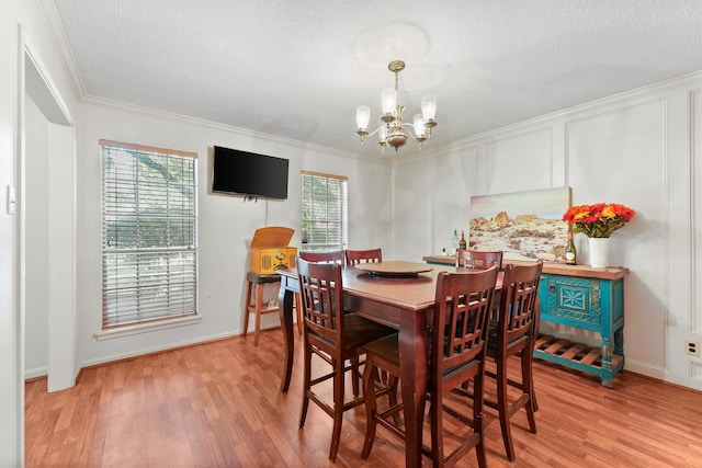 dining space featuring a notable chandelier, light wood-type flooring, ornamental molding, and a healthy amount of sunlight