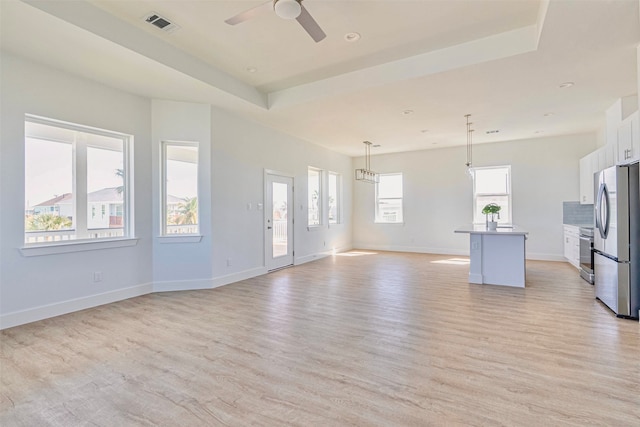 kitchen with pendant lighting, a kitchen island with sink, white cabinetry, appliances with stainless steel finishes, and light hardwood / wood-style floors