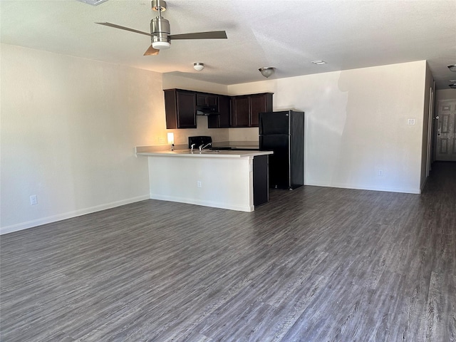 kitchen featuring kitchen peninsula, black fridge, ceiling fan, sink, and dark hardwood / wood-style floors