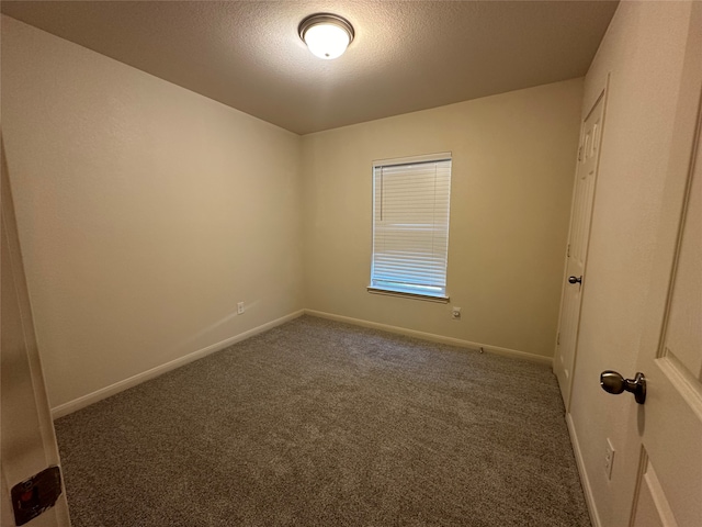 unfurnished room featuring dark colored carpet and a textured ceiling