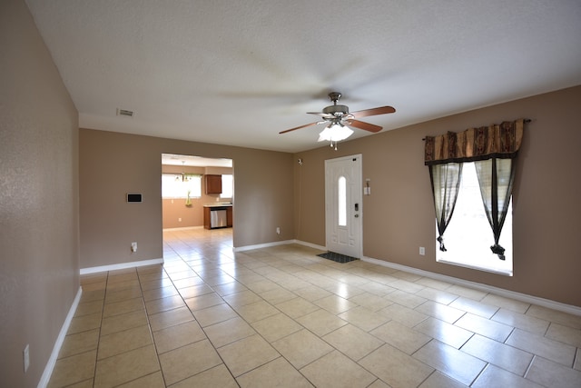 spare room with ceiling fan, light tile patterned floors, and a textured ceiling