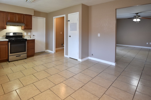 kitchen with stainless steel gas range, ceiling fan, and light tile patterned floors