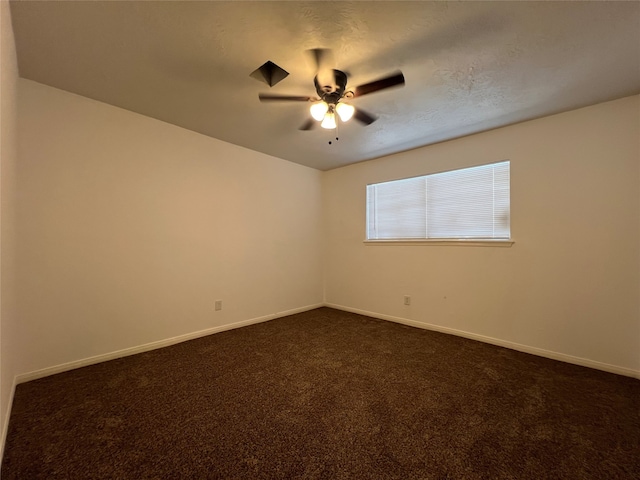 empty room with ceiling fan, dark carpet, and a textured ceiling