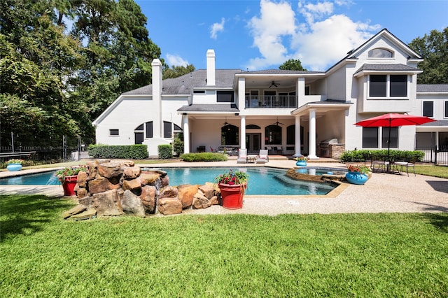 rear view of property with a balcony, ceiling fan, a fenced in pool, and a patio area