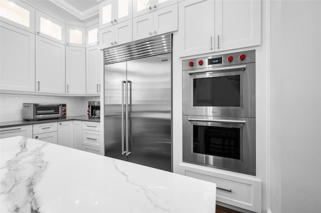 kitchen with dark stone counters, white cabinets, and appliances with stainless steel finishes