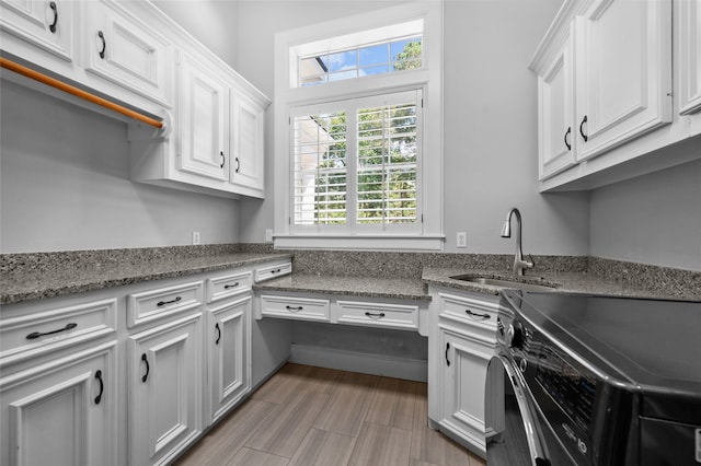 kitchen with white cabinets, dark stone counters, and sink