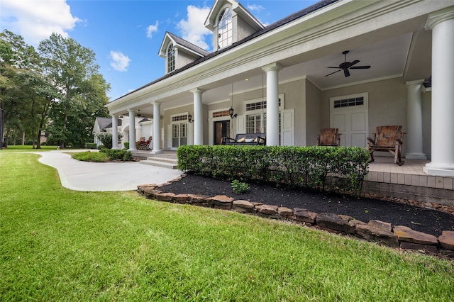 entrance to property with a lawn, a porch, and ceiling fan