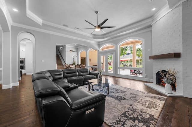 living room with a fireplace, ornamental molding, dark hardwood / wood-style flooring, and ceiling fan