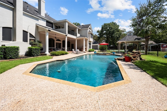 view of swimming pool with a lawn, a gazebo, ceiling fan, and a patio area