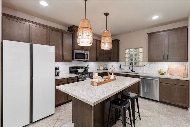 kitchen featuring pendant lighting, sink, appliances with stainless steel finishes, tasteful backsplash, and a kitchen island