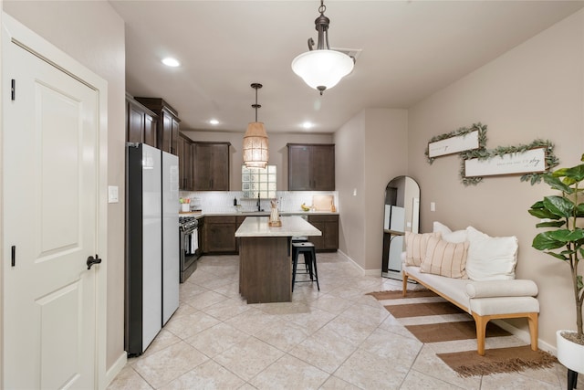 kitchen featuring a breakfast bar area, a center island, dark brown cabinets, white fridge, and pendant lighting