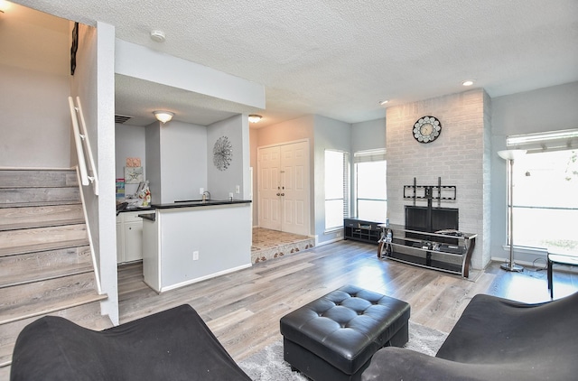 living room featuring a textured ceiling, light wood-type flooring, and sink