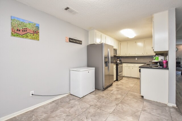 kitchen with decorative backsplash, appliances with stainless steel finishes, a textured ceiling, sink, and white cabinetry