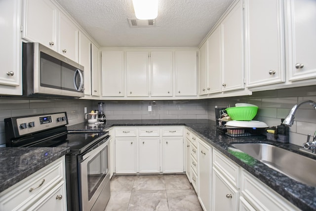 kitchen featuring appliances with stainless steel finishes, tasteful backsplash, white cabinetry, and sink