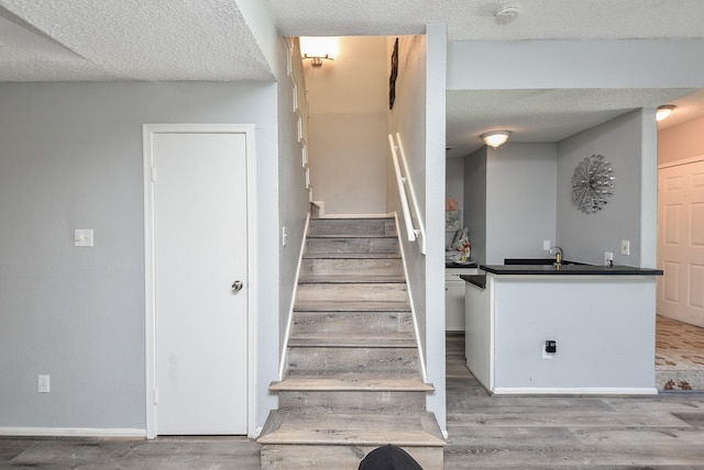 stairs featuring wood-type flooring and a textured ceiling