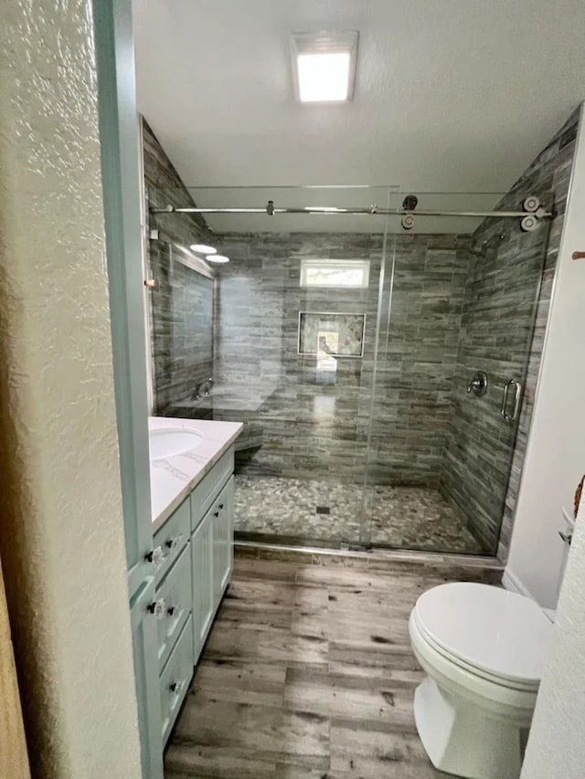 bathroom with vanity, an enclosed shower, wood-type flooring, a textured ceiling, and toilet