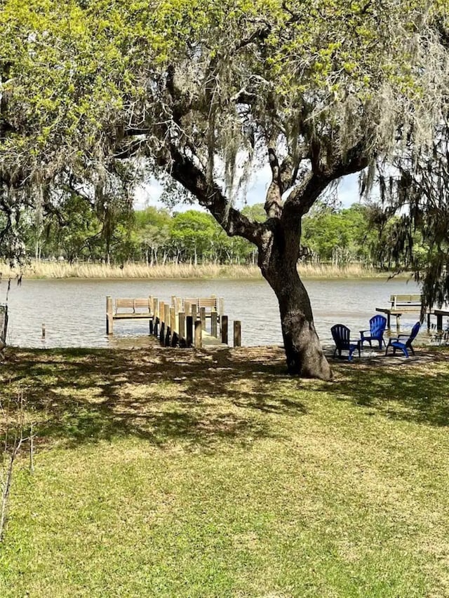 view of dock featuring a lawn and a water view