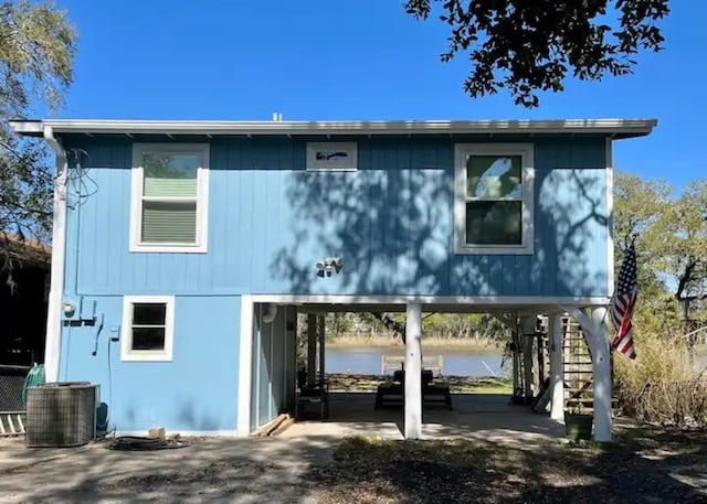 rear view of house featuring cooling unit, a water view, and a patio area