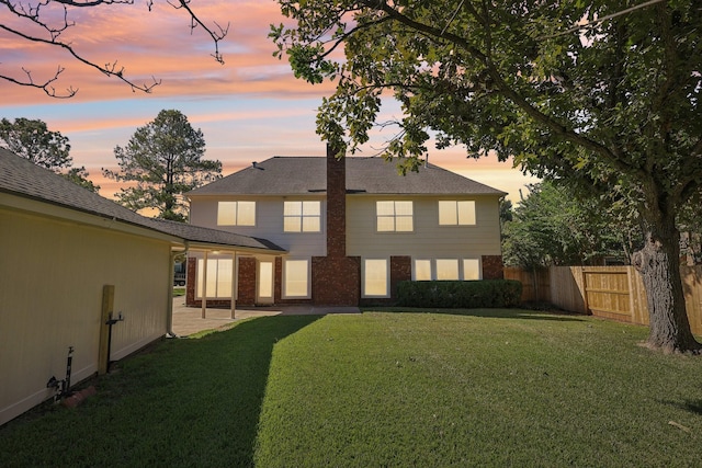 back house at dusk featuring a lawn