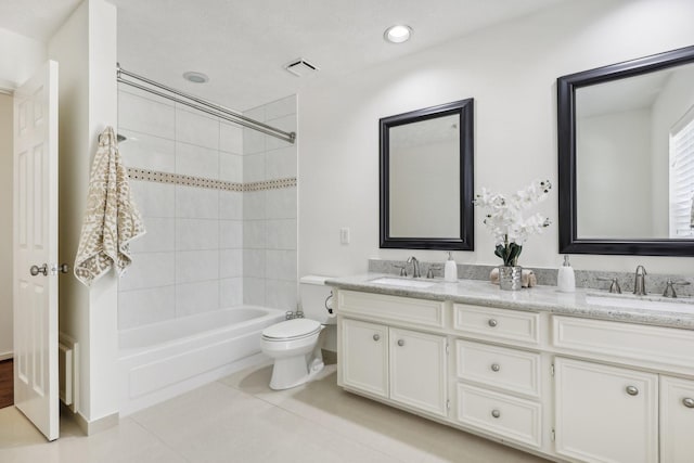 full bathroom featuring tile patterned floors, vanity, tiled shower / bath combo, and toilet