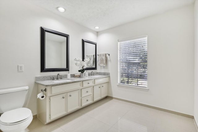 bathroom featuring tile patterned flooring, vanity, toilet, and a textured ceiling