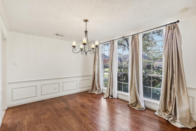 unfurnished dining area featuring a notable chandelier, dark hardwood / wood-style flooring, ornamental molding, and a textured ceiling