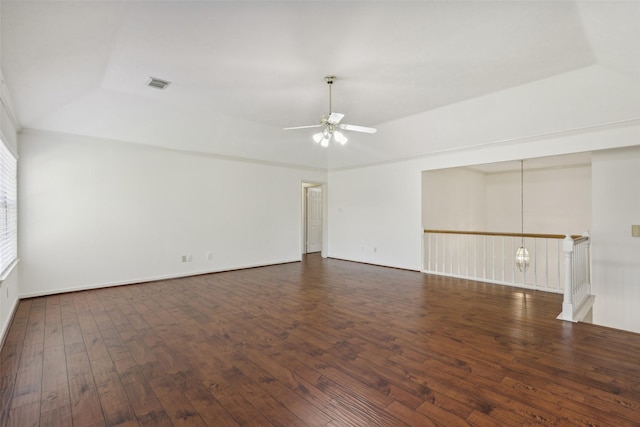 empty room with ceiling fan with notable chandelier, dark hardwood / wood-style floors, and a tray ceiling