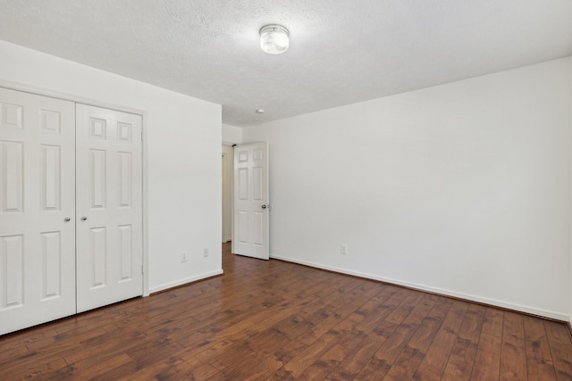 unfurnished bedroom with dark hardwood / wood-style floors, a textured ceiling, and a closet