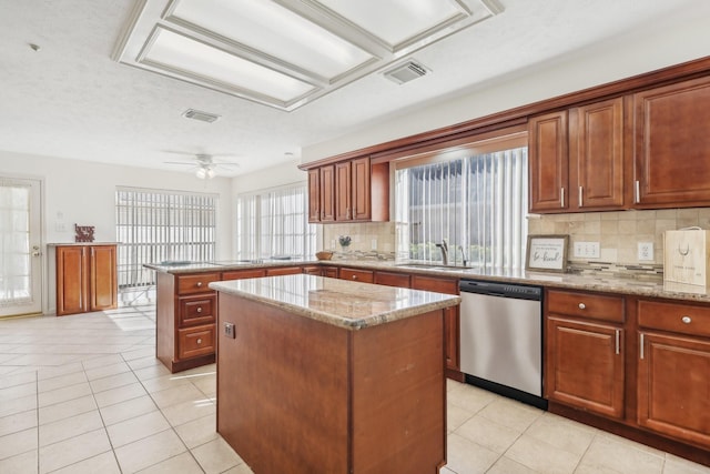 kitchen featuring tasteful backsplash, stainless steel dishwasher, ceiling fan, sink, and a kitchen island