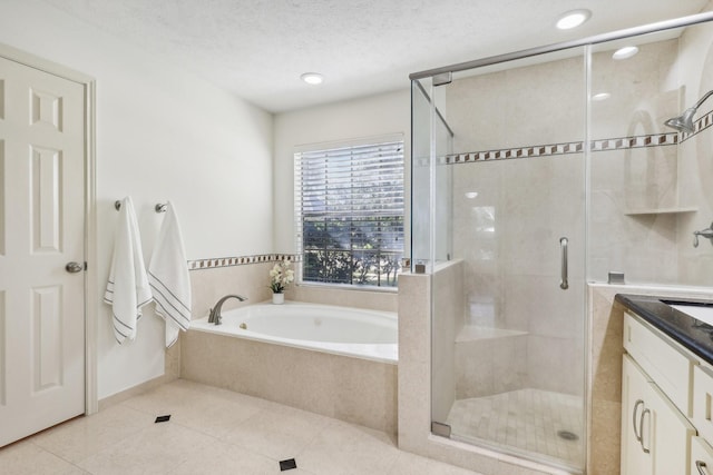 bathroom with tile patterned flooring, vanity, shower with separate bathtub, and a textured ceiling