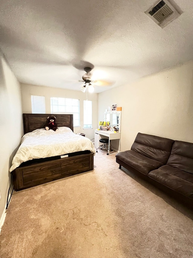 carpeted bedroom featuring ceiling fan and a textured ceiling