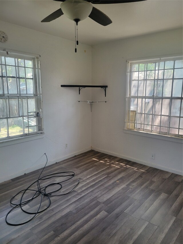 empty room with ceiling fan, plenty of natural light, and dark wood-type flooring