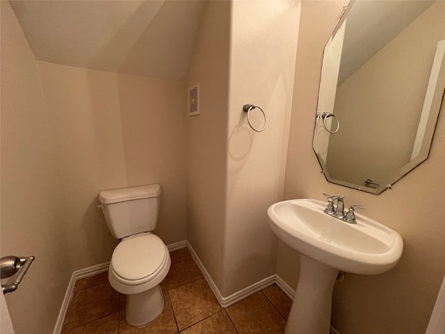 bathroom with tile patterned flooring, vaulted ceiling, and toilet