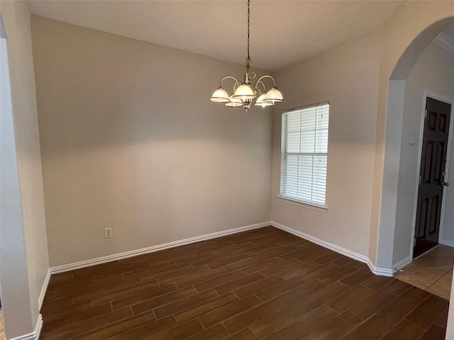 empty room with an inviting chandelier and dark wood-type flooring