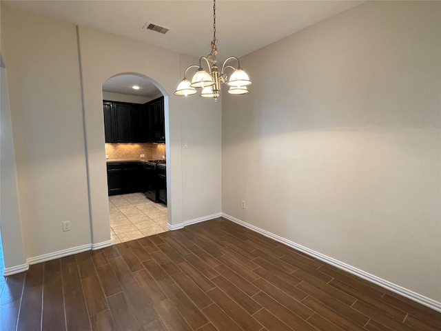 unfurnished dining area with an inviting chandelier and dark hardwood / wood-style flooring