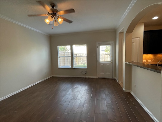 empty room featuring ceiling fan, crown molding, and dark wood-type flooring