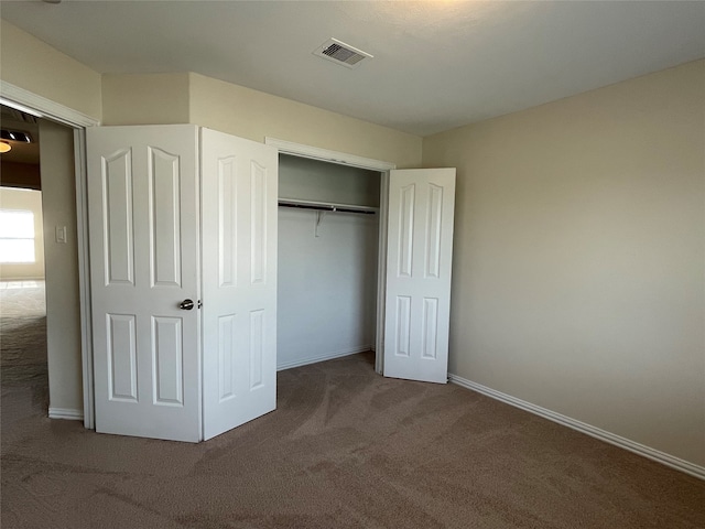 unfurnished bedroom with a closet and dark colored carpet